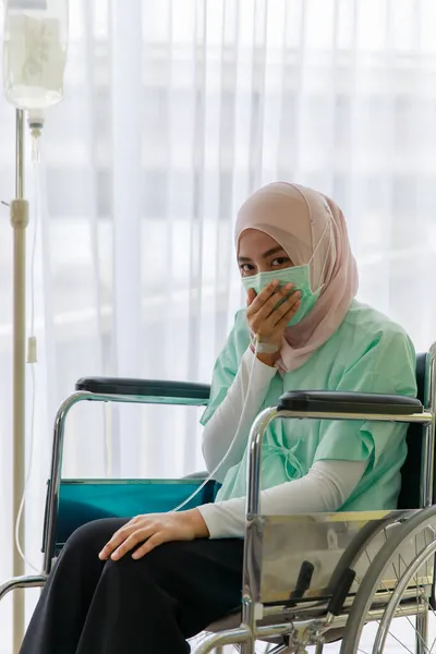 病気の肖像患者のガウンを着て 病院で生理食塩水の袋を添付して車椅子に座っているイスラム教徒の顔のマスク Covid 19パンデミックの概念 — ストック写真