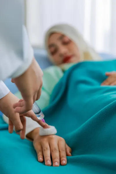 病院のベッドに横たわっている若いイスラム教徒の患者にワクチンを注射するための医療注射器を準備する医師 コンセプトCovid 19ワクチン接種 — ストック写真