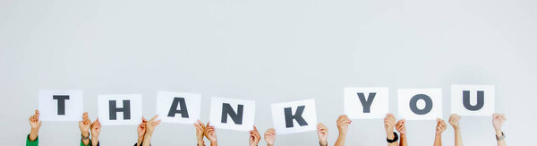 Studio shot of unrecognizable unidentified group of staff officer in corporate office holding thank you alphabet cardboard paper sign over head showing appreciation to customer on white background.