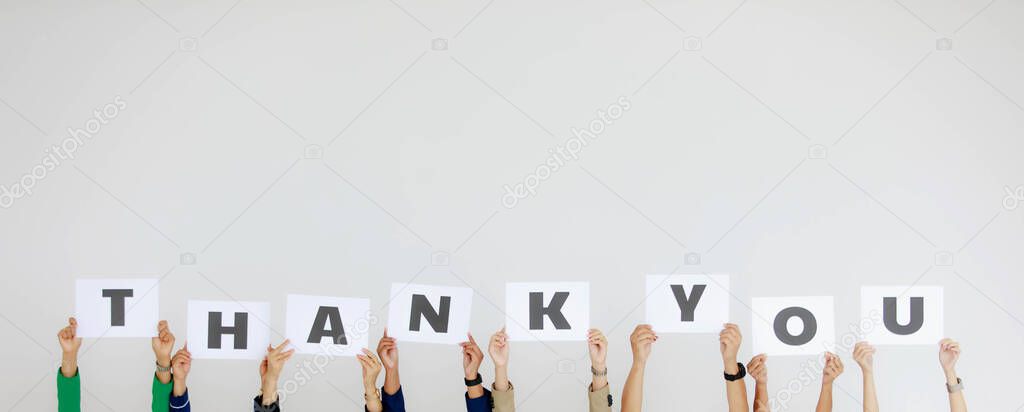 Studio shot of unrecognizable unidentified group of staff officer in corporate office holding thank you alphabet cardboard paper sign over head showing appreciation to customer on white background.