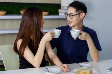 Birlikte kahve içen ve sıcak mutfakta oturan güzel Asyalı çiftin yakın portresi. Bu aşıkların boş zamanlarında yaptıkları bir şey..