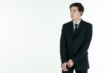 Kendine güvenen genç ve yakışıklı Asyalı iş adamının portresi beyaz arka planda izole edilmiş fotokopi stüdyosuyla şık duruşu olan siyah elbiseyi düzenleyip ayarlıyor..