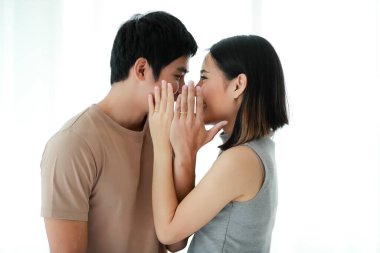 Asyalı genç çiftin portre fotoğrafı. Birbirlerine yakından bakıp, beyaz arka planda yüzük takan altın nişan yüzüklerini gösteriyorlar..