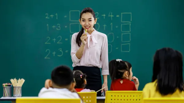 아시아의 아름다운 여교사가 분필을 분필을 교실에서 남학생 여학생을 가르치는 모습의 — 스톡 사진