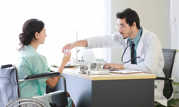近代病院の入院中に車椅子の女性に薬を飲ませて制服を着た男性医師 — ストック写真