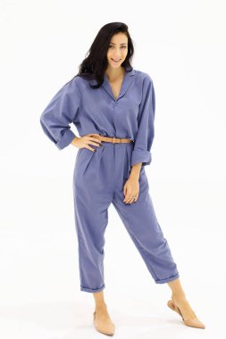 Mavi iş elbiseli beyaz Avrupalı bir kadın portre için ayakta duruyor. Beyaz insanlar beyaz arka planda güzel bir portre stüdyosu.