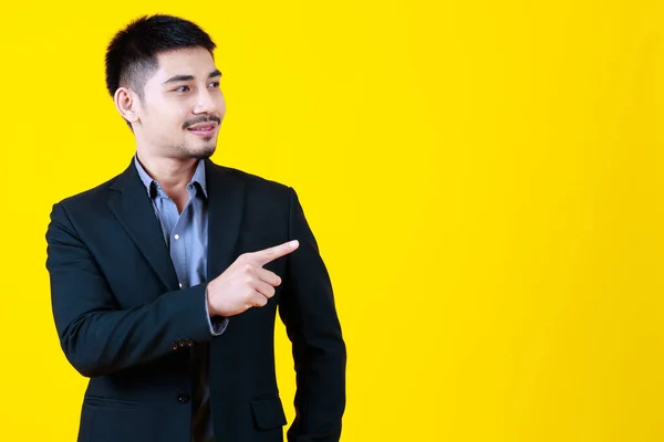 アジアのビジネスひげハンサムな大人の男は 正式なスーツを着て 手を上げ 提示し 側面の空白のスペースを指摘し 驚きのジェスチャーを作り 孤立した黄色の背景に立って — ストック写真