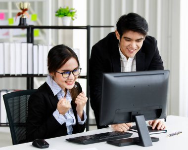 Modern gözlük takan zeki genç iş kadını bilgisayarla birlikte çalışıyor. Yanında duran genç adam ekrana bakıyor ve tartışıyor. Takım çalışması konsepti