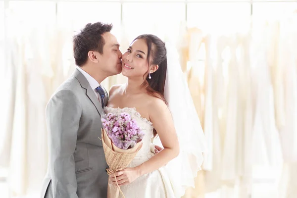 新郎と新婦は 花嫁のドレスを背景に 笑顔で抱き合って立っています アジア人男性甘い頬は女性への愛を表します コンセプト素敵な結婚式の最高の日 — ストック写真