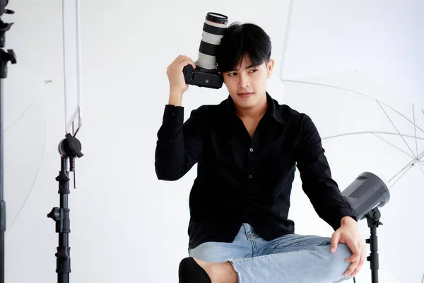 Asyalı Yakışıklı Erkek Fotoğrafçı Günlük Siyah Gömlek Giyiyor Kamerayı Tutuyor — Stok fotoğraf