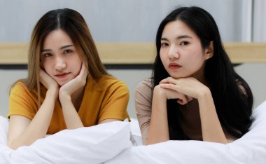 Gülümseyen iki Asyalı genç kadın güzel çift beyaz yatakta oturuyor ve mutlu. Komik kadınlar uyandıktan sonra samimi olurlar. Aşık homoseksüel lezbiyen lgbt, lgbtq, lgbtq+