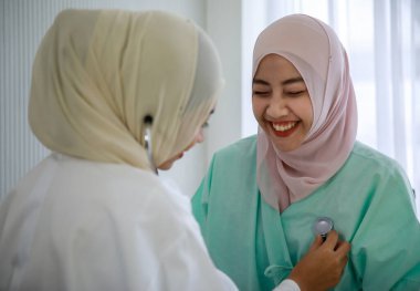 Genç kadın müslüman doktor hastanede steteskopla Müslüman hastanın kalbini kontrol ediyor..