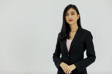 Asyalı genç, zeki, kendinden emin, mutlu, profesyonel, başarılı, siyah takım elbiseli kadın iş kadınının beyaz arka plandaki kameraya gülümseyen bir fotoğrafı..