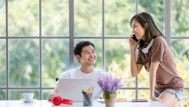 İç işlerinde dizüstü bilgisayar ve not defteri kullanarak proje üzerinde çalışan Asyalı genç işadamları rahat tişörtler giyiyorlar. Kulaklıkla müzik dinleyen bir bayan rahat bir tişört giyerken. Bu arada bayan telefonda konuşuyor.