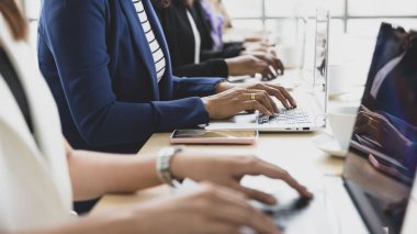 Ofisteki konferans masasında dizüstü bilgisayarda oturan ve çalışan birden fazla iş kadınının ellerine odaklan. İş görüşmesi için kavram.