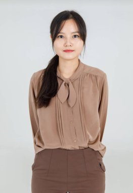 Sevimli Asyalı kız güler yüzlü, güler yüzlü, güler yüzlü, çekici kahverengi bluzu olan ve kadın yaşam tarzı için oldukça sıradan bir kıyafet olan güler yüzlü, güler yüzlü.