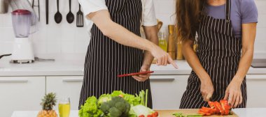 Önlüklerle tanınmaz halde tezgahta sıcak içecekler içiyorlar. Mutfakta modern mutfak gereçleri ve çeşitli ürünler var.