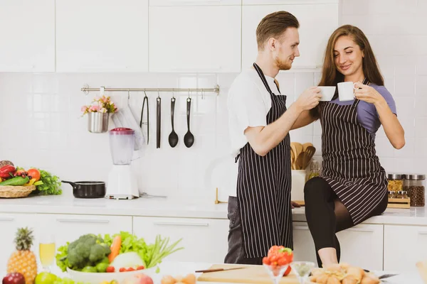 Encantada Pareja Delantales Bebiendo Bebidas Calientes Mostrador Con Utensilios Cocina — Foto de Stock