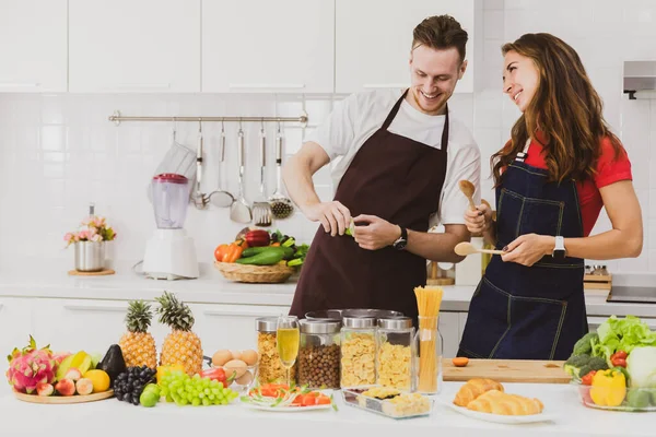 Casal Feliz Aventais Mesa Com Vários Produtos Enquanto Cozinham Juntos — Fotografia de Stock