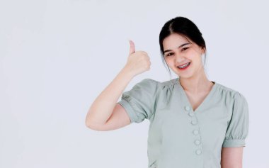 Asyalı, genç, somurtkan, at kuyruğu saç stili, sıradan giyinmiş, beyaz arka planda el ele tutuşmuş, asyalı, asık suratlı kadın modelin portresi..