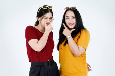 Moda gözlüklü, birbirine dokunan güneş gözlüğü takan, havalı, moda modası geçmiş iki Asyalı genç modelin belden omuz omuza durduğu bir portre resmi. Beyaz arka plandaki kameraya bakın..