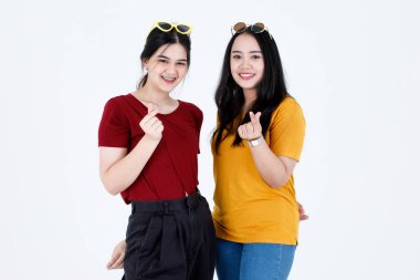 Portre stüdyosu iki genç Asyalı havalı moda kadın arkadaş resmi çekti. Günlük kıyafetler ve moda güneş gözlüğü takmış modeller. Gülümse..