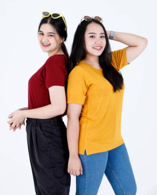 Portre stüdyosu iki genç, güzel Asyalı, şık moda bayan arkadaş modeli günlük kıyafetler ve moda güneş gözlüğü takmış beyaz arka plandaki kameraya gülümseyen bir şekilde çekti..