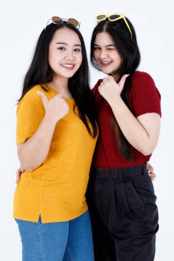 Portre stüdyosu, iki güzel Asyalı, şık moda bayan arkadaş resmi çekti. Günlük kıyafetler ve moda gözlükleri takmış, gülümseyen, gülümseyen, beyaz arka planda sarılan kameralara bakıyordu..