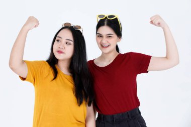 Portre stüdyosundaki iki güzel Asyalı kız arkadaşın gündelik tişört giymiş, gözlüklü, gülümseyen, beyaz arka planda kaslı kasları olan iki genç kız arkadaşının portresi..