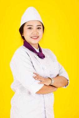 Asyalı profesyonel, başarılı, kendine güveni tam bir otel restoranının portre stüdyosu. Beyaz üniformalı kadın yönetici. Sarı arka planda kollarını kavuşturmuş kameraya gülümsüyor..