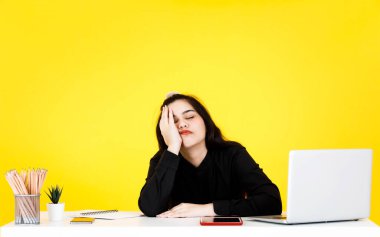 Asyalı, yorgun, uykulu, siyah elbiseli kadın iş kadınının, çalışma masasında sarılar üzerinde el ele çalışırken çekilmiş bir portre resmi..