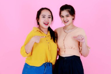 İki Asyalı mutlu, neşeli bayan arkadaşın, günlük kıyafet giyip diş telleri takıp, pembe arka planda el ele tutuşup kameraya gülümseyen iki fotoğrafının portresi..