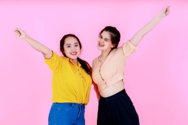 İki Asyalı mutlu, neşeli bayan arkadaşın, günlük kıyafet giyip diş telleri takıp, pembe arka planda el ele tutuşup kameraya gülümseyen iki fotoğrafının portresi..