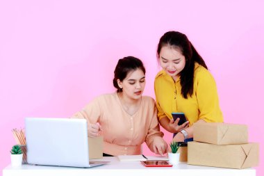 Stüdyo, iki Asyalı mutlu, başarılı, profesyonel kadın girişim küçük iş kadını, gülümseyen ve pembe arka planda birlikte çalışan iş kadını çekti..