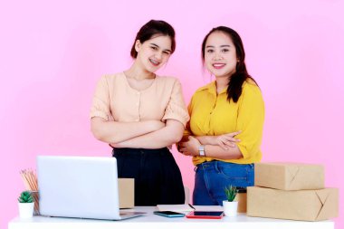 İki Asyalı, mutlu, profesyonel, genç ve başarılı bayan girişimci iş kadınının portre çekimi. Küçük girişimci iş kadını, pembe arka planda birlikte kameraya bakıp gülümsüyor..
