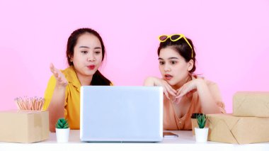 İki Asyalı 'nın stüdyo çekimi şoke edici bir sürpriz oldu. Yeni başlayan küçük iş kadını iş ortağı. Müşteri pembe arka planda büyük bir alışveriş yaptığında dizüstü bilgisayara bakın..