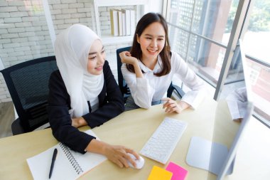 Asyalı iş kadını ve Müslüman patronun modern ofiste iyi bir ruh haliyle programları hakkında konuştuğu yüksek açılı bir çekim..