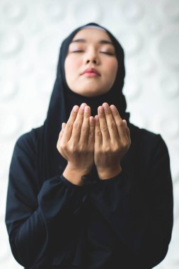 Asya 'lı güzel Müslüman kadının tesettürlü görüntüsünü yakınlaştır. Tanrı' ya inandığını gösteren dualar et..