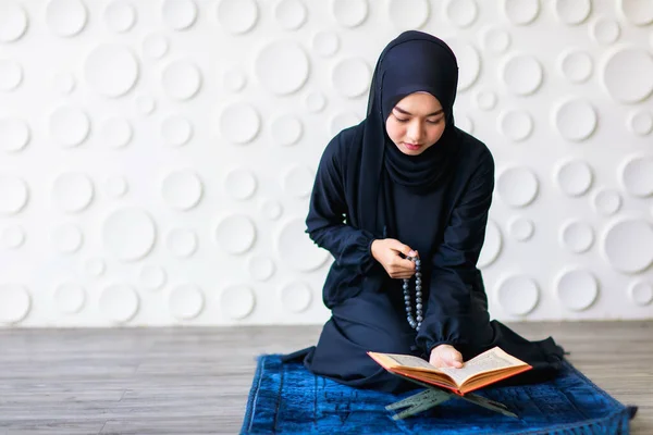 ヒジャーブでアジアの美しいイスラム教徒の女性のショットでズーム1日の祈りを行います 彼女はカーペットの上に座り 神を信じることを示すビーズを手に持っています — ストック写真