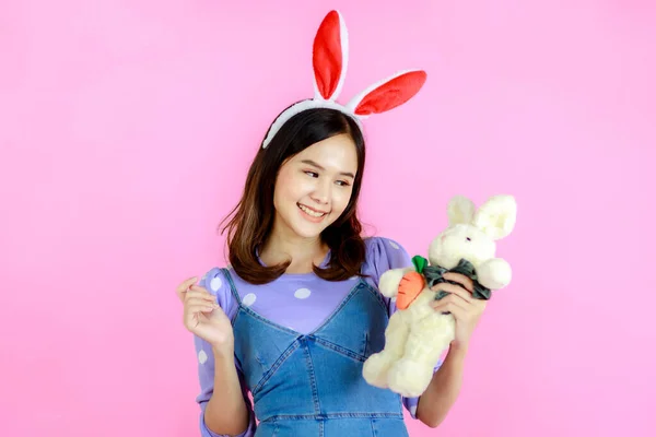 准备迎接复活节的亚洲美女近照 她抱着兔子娃娃 快乐地与粉红的背景隔离在一起 — 图库照片