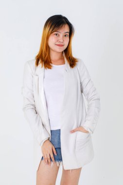 Asyalı modaya uygun kentsel güzel mutlu saç modelinin uzun bir takım elbise ve kot pantolon giymiş beyaz arka planda poz veren kameraya bakarken çekilmiş bir portre resmi..