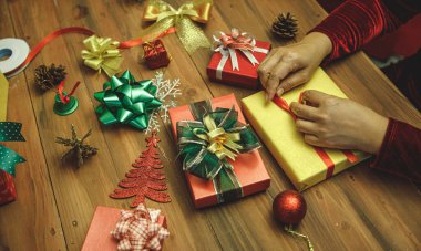 Güzel hediye kutusu ahşap masa üzerinde renkli büyüleyici bir fiyonk ile süslenmiş. İnsanlar kış tatilinde muhteşem bir aile partisi için Noel hediyesi olarak paketliyor. Eski tarz resme uyması için biraz gürültü ekle.