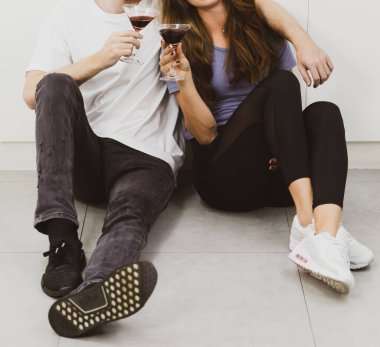 Tanımlanamayan bir çift içki içerken tezgahta çeşitli malzemeler ve açık modern mutfakta beyaz dolaplarla oturuyorlar.