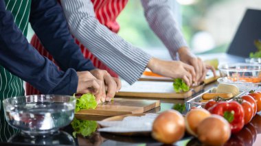 Profesyonel şefler domates, soğan ve el karışımı taze malzemelerle sağlıklı vejetaryen yemekleri pişirmek için mutfak mutfağındaki ahşap tepside yıkanmış organik sebzelerle karıştırıyorlar..