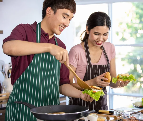 아시아의 요리사는 식당에서 야채와 맛있는 햄버거를 요리하는 스러운 도움을 주면서 — 스톡 사진