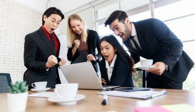 Hayretler içinde kalmış çok ırklı iş arkadaşları çalışma sırasında açık konferans odasındaki bardaklarla birlikte masada sörf ağı takıyor.