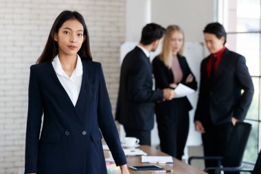Resmi görevdeki bir grup pozitif çok ırklı işçi toplantı sırasında konferans odasında dikilirken kameraya kollarını kavuşturarak bakıyorlar.