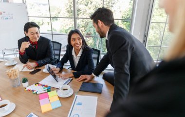 Toplantı sırasında elinde tabletler ve yapışkan notlarla masada oturan pozitif çok ırklı iş arkadaşlarının yanında yüzü olmayan ekinsiz bir işçi.