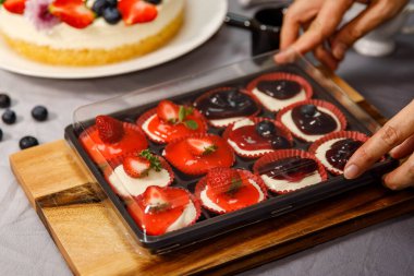 Tatlı cheesecake mini taze meyvelerle süslenmiş, ve tahta bir tabakta çiçekler, doğum günü, sevgililer günü ve kutlama için.