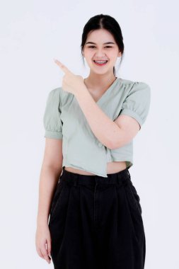 Atkuyruklu, diş teli takan, diş teli takan ve el ele tutuşup beyaz arka planda kahkahalarla gülen Asyalı genç ve komik genç kız modelinin stüdyo fotoğrafı..